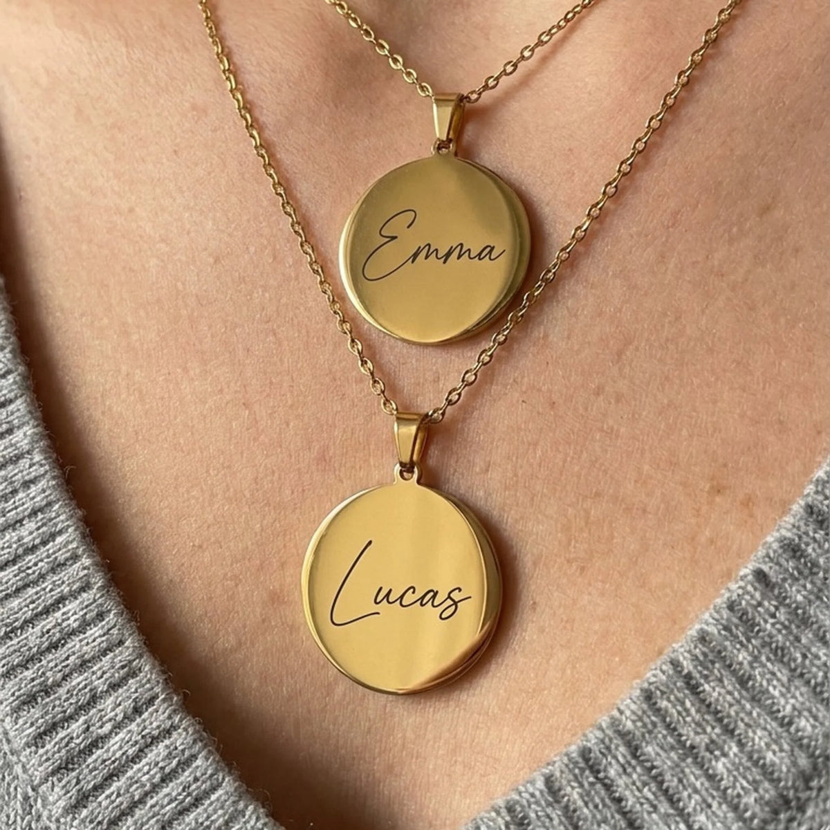 Deux colliers gravés aux prénoms Emma et Lucas, pendentifs ronds plaqués or portés au cou